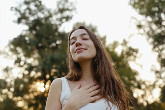 The woman standing outdoors eyes closed hand on chest serene golden-hour portrait