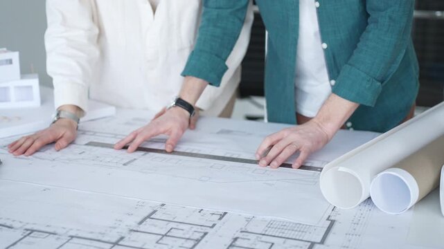 Architects discussing apartment building blueprint at office desk, using drafting tools for new architectural project design. Architecture and business concept