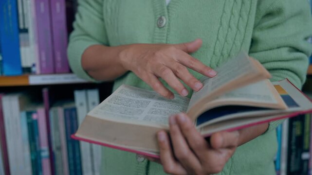Close-up hand's woman reading book in library.