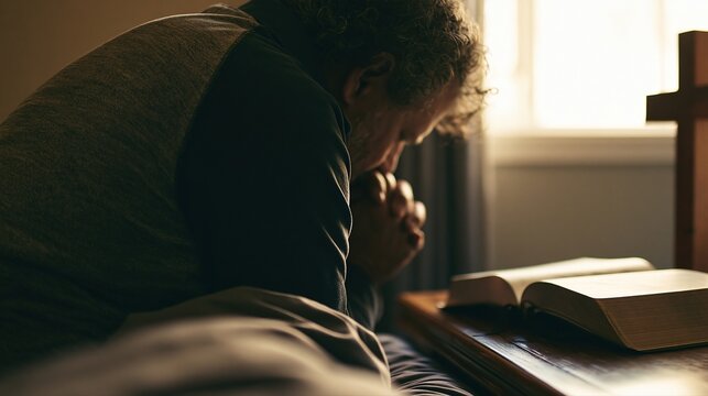 Man Praying Beside Open Bible and Cross in Soft Morning Light, Christian Devotion Concept