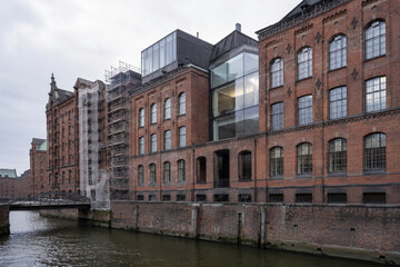 Naklejka premium Historic Brick Warehouses by Canal with Glass Rooftop Addition at Waterfront