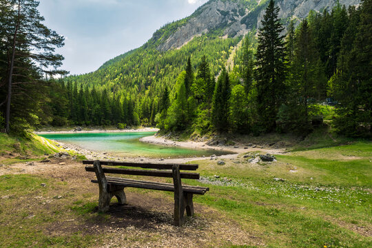 Wooden bench overlooking the Gruner See in Austria, surrounded by mountains, evoking mental restoration through nature retreats