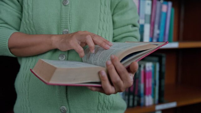 Close-up hand's woman reading book in library.