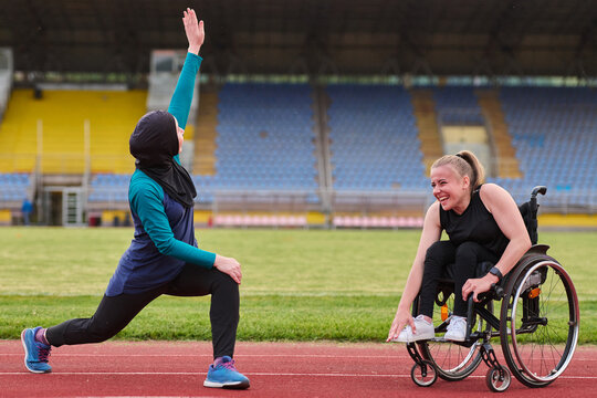 Adaptive Fitness on the Track Wheelchair Athlete and Hijab Wearing Runner Stretching Together