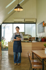 Obraz premium Young Asian woman cafe owner standing smiling in her small coffee shop. Holding a digital tablet for managing orders and business operations