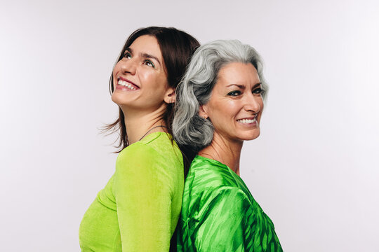 Two women standing back to back smiling