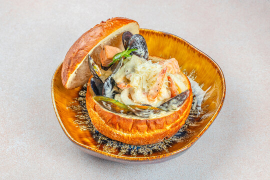 Creamy seafood chowder served in bread bowl with mussels shrimp and salmon