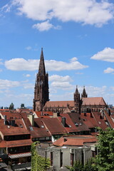 Fototapeta premium Der Freiburger Münsterturm hinter Hausdächern