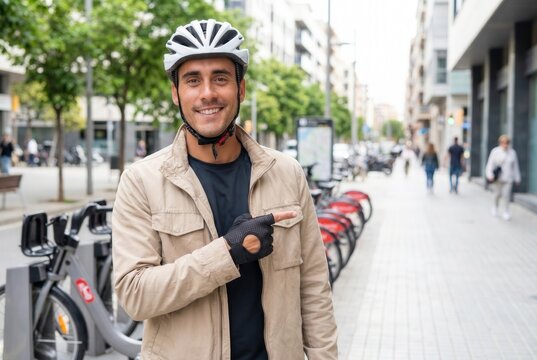 Young man standing near a bike rental station, pointing with his finger