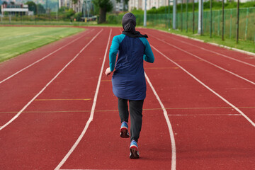 Fototapeta premium Woman in Hijab Running on Outdoor Track for Fitness and Endurance Training