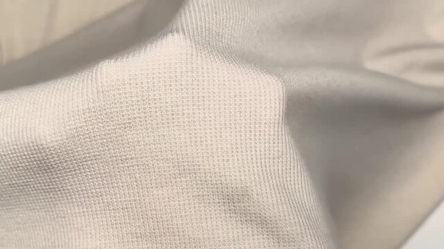 This knit fabric features a beige hue with a textured pattern and a soft drape that holds its shape and provides comfort for various seasonal garment projects.