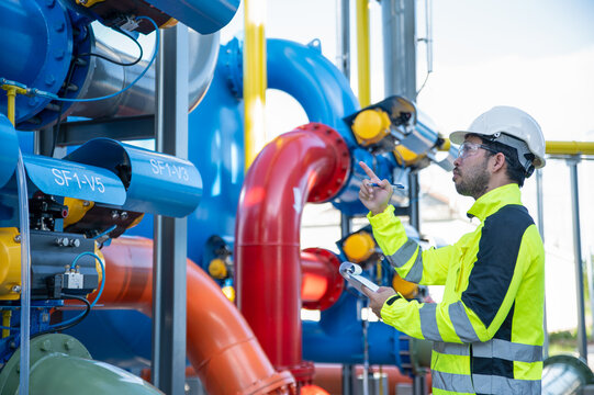 A skilled technician is testing the operation of the oil refining system at a large oil refinery.