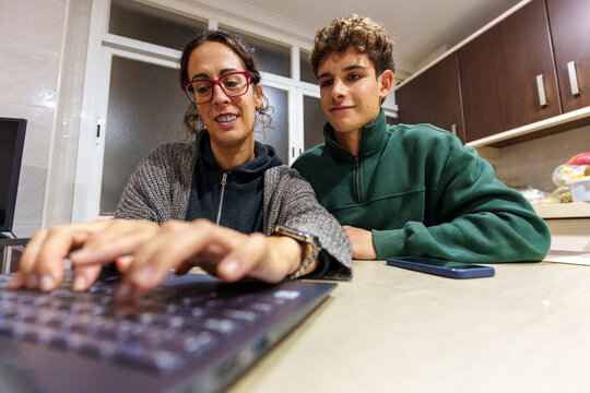 Teenage son teaching mother about computer technology, bridging generational gap in digital learning at home