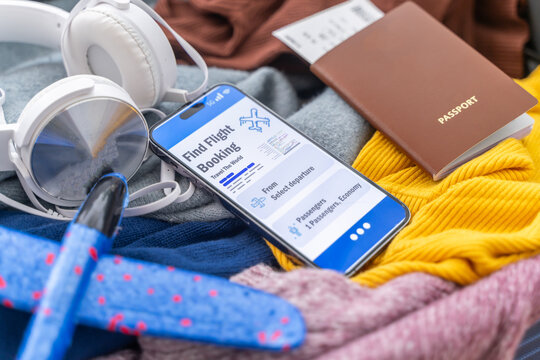 Flight booking online app with smartphone, passport and boarding pass on a packed suitcase, Concept of travel planning, airline ticket reservation, summer holiday trip and vacation departure tour