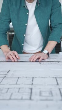 Architect drawing on blueprint plans with ruler and pen, designing new building construction project, engineering workspace. Architecture and business concept