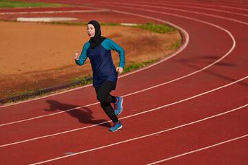 Fototapeta premium Muslim Woman Running on Outdoor Track in Hijab Wearing Athletic Clothes for Fitness Training