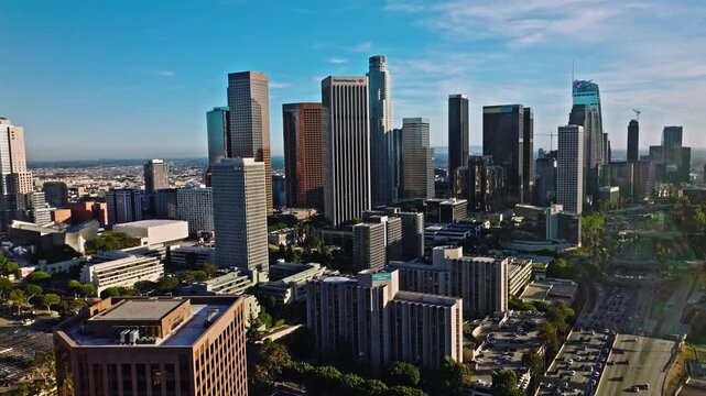 Aerial view of downtown Los Angeles skyline and busy freeway traffic at sunset.