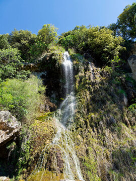 Impressive Villecroze waterfall in Provence in the Haut-Var region flows down a high tuf a cliff overlooking parks and flower gardens
