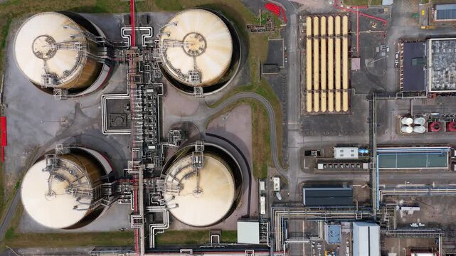 Top down aerial drone shot of massive circular liquefied natural gas LNG storage tanks on the Isle of Grain UK