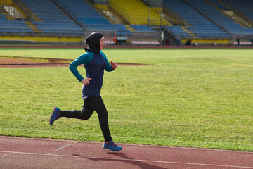 Fototapeta premium Female Runner in Headscarf Training on Outdoor Track in Stadium for Fitness and Running