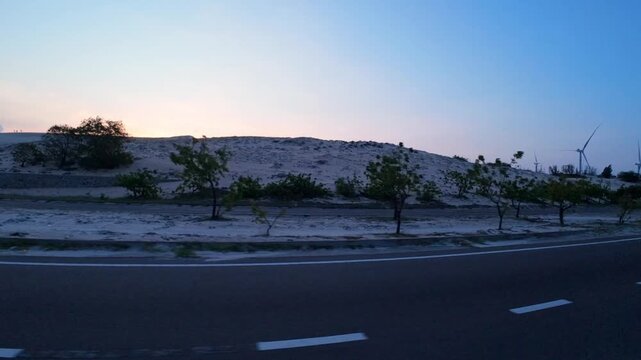 Side view POV of driving along the empty Bau Trang desert highway under a dramatic sunset sky.