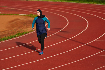 Fototapeta premium Muslim Woman Runner Wearing Hijab Training Alone On Outdoor Red Track For Fitness