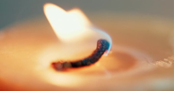 An extreme macrocloseup of a candle wick burning with a soft orange flame. Ideal for wellness, meditation, and relaxation content.
