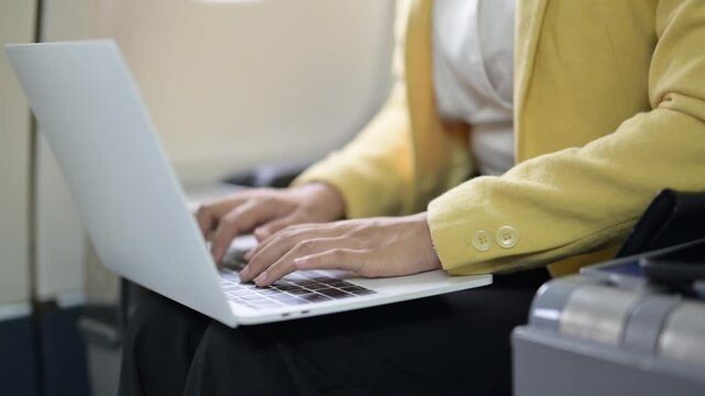 Businesswoman typing on laptop during airplane travel