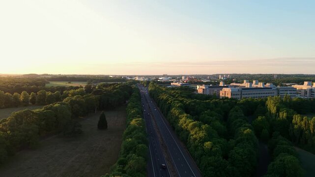 Aerial view of the GSK corporate building and busy traffic on the A1 road at sunset, UK.