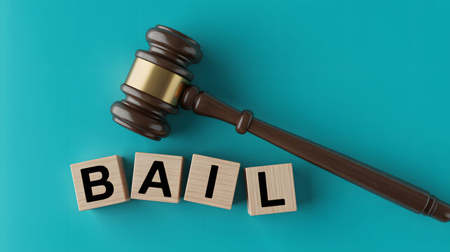 A gavel and wooden blocks spelling out bail on a teal background in a courtroom setting.