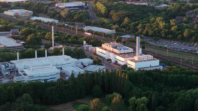 Drone shot of modern science park offices alongside a busy trunk road during golden hour, United Kingdom.