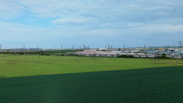 Rising aerial view of freight train passing industrial port near Tilbury on River Thames