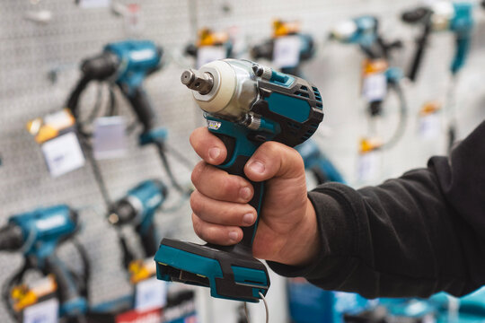 Hand holding cordless impact wrench in hardware store or power tools shop showcasing professional construction equipment selection. Industrial building device.