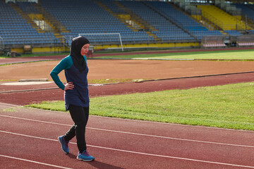 Fototapeta premium Muslim Woman Exercising on Outdoor Running Track at Empty Sports Stadium in Hijab Workout Gear