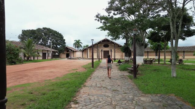 Woman walks past park on stone sidewalk toward San Javier Cathedral