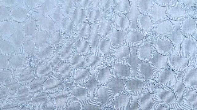 This light blue cotton fabric features an intricate embossed floral pattern created with ribbon strips, offering a lightweight and comfortable texture ideal for dresses and apparel