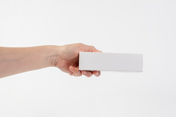 Obraz premium A white product box in hand, against a white background. Packaging box.