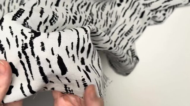 The soft textile blend showcases a bold black abstract dash print on a crisp white background making it an ideal choice for stylish summer apparel and dresses.