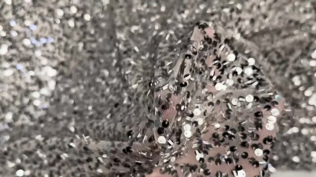Sparkling silver paillettes stitched densely on sheer mesh background creating reflective texture suitable for formal dresses and decorative fashion projects.