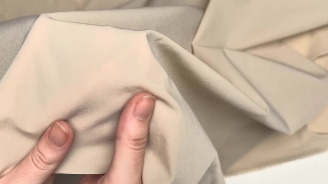Smooth beige stretch textile with subtle texture presenting flexible material suitable for sewing lightweight outerwear and comfortable everyday clothing items.