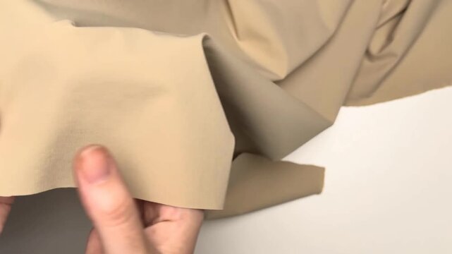 Smooth water repellent beige bi stretch nylon spandex textile presenting a flexible material suitable for sewing lightweight outerwear and activewear clothing items.