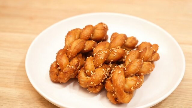 Sesame Mahua (Fried Dough Twists) Traditional Chinese Crispy Snack Stacked on White Plate