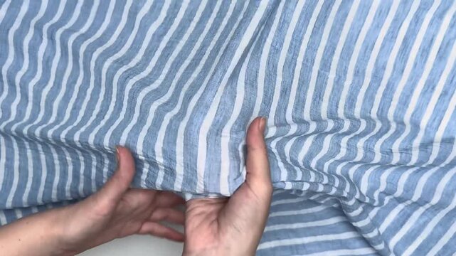 Blue and white striped textile material featuring a sheer and lightweight texture, showcasing vertical lines suitable for stylish summer apparel and casual dressmaking projects.