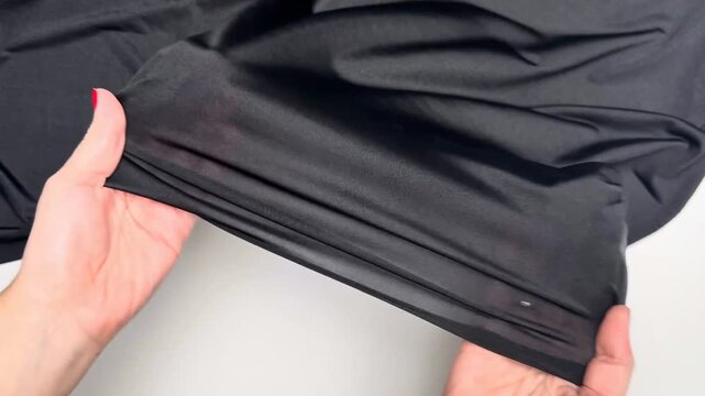 Black lycra knit fabric close up showing smooth sleek texture elastic surface pattern and flowing material suitable for apparel garment and sewing projects.