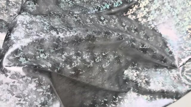 Silver stretch knit textile displaying an intense iridescent crushed foil effect with sparkling reflections featuring an elastic texture suitable for unique fashion apparel projects.