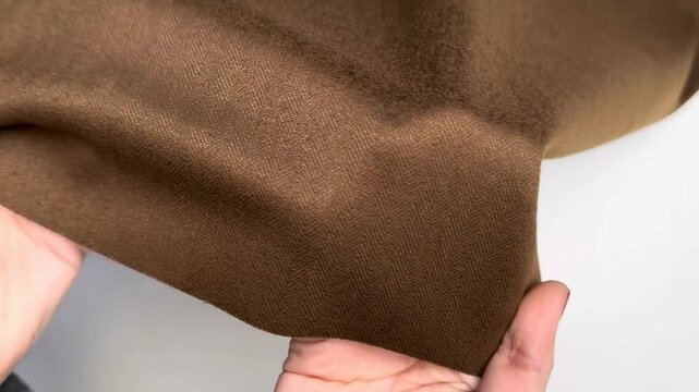 Brown knit fabric with a soft fleecy front and smooth wrong side presenting elastic properties and density suitable for warm apparel manufacturing and textile industry applications.
