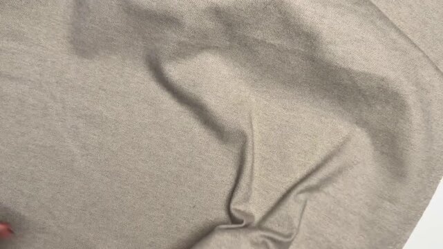 Beige warm knit fabric with a soft fleecy side and smooth texture presenting elastic properties and density suitable for winter apparel manufacturing and textile industry applications.