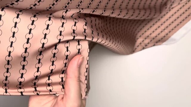 Dusty pink polyester spandex silk satin textile showcasing a dark chain pattern suitable for creating elegant blouses and dresses with a smooth glossy surface and lightweight drape