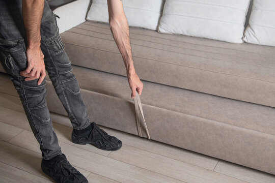 Man open a convertible sofa at home.