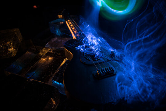 Music Concept: Guitar Miniature on a Dark Background with Vivid Light, Smoke, and Fire Effects. Golden electro guitar under a Dramatic Spotlight.